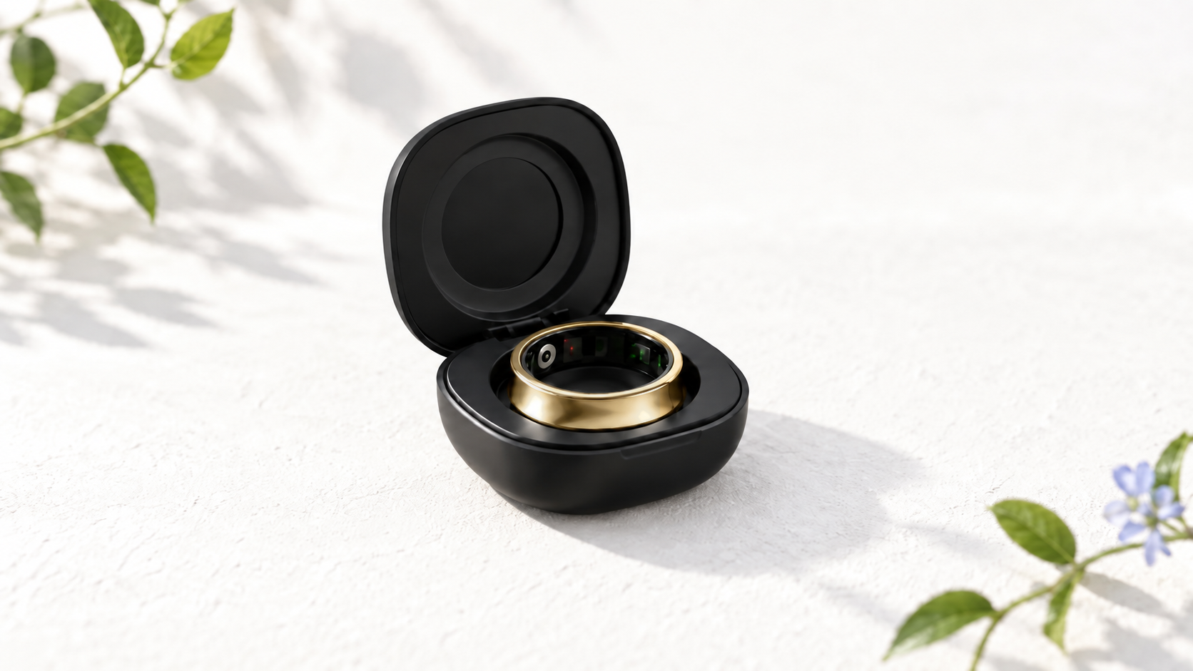 Open black Rune 1 charging case holding a silver smart ring, resting on a white surface among green leaves and soft vine shadows.