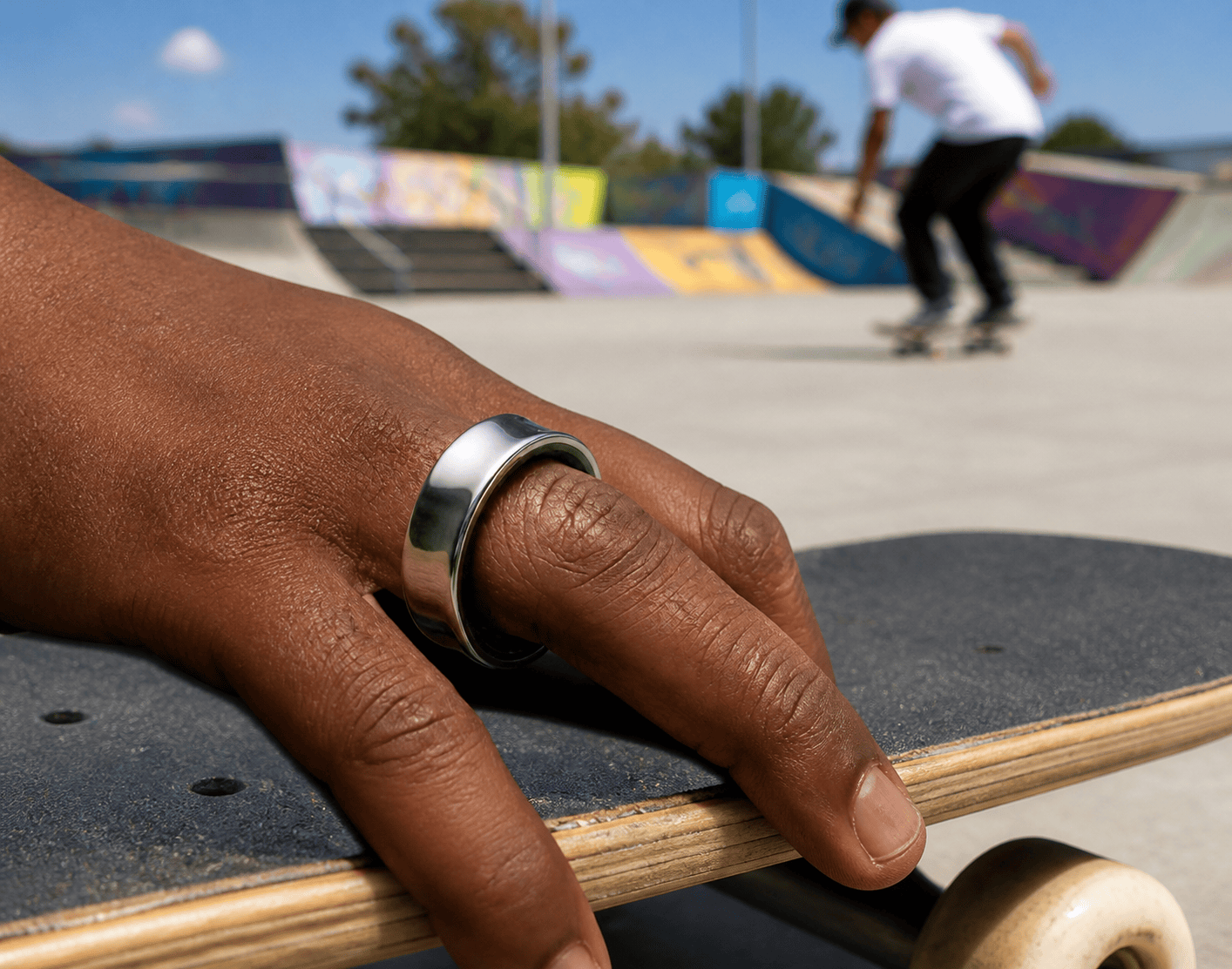 A polished silver ring on a hand, resting on a dark, coarse-textured surface.
