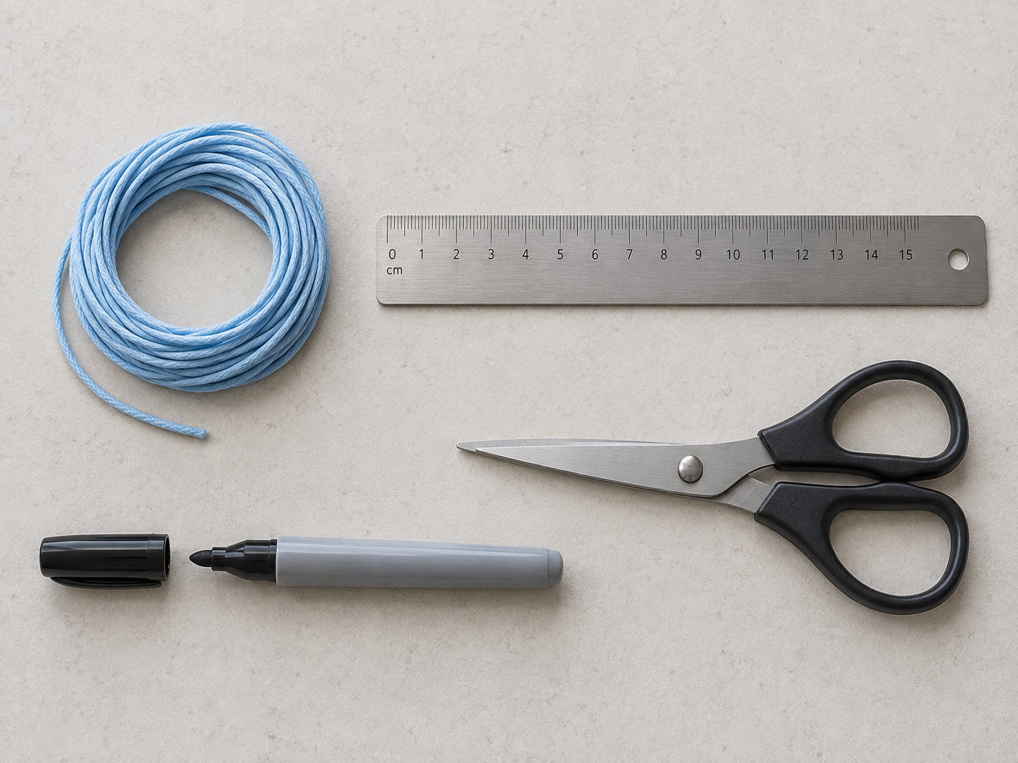 String, scissors, pen, and metric ruler laid out on a plain surface